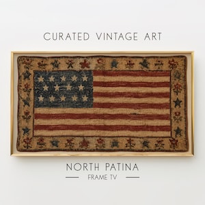 Pode incluir: Uma obra de arte retangular emoldurada com um design de tapete de gancho de uma bandeira americana com um cantão azul escuro de estrelas e listras vermelhas e brancas, cercada por uma borda de estrelas e flores. Texto: CURATED VINTAGE ART NORTH PATINA FRAME TV.