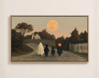 May include: A framed horizontal wall art print depicting a rural landscape at twilight with a large full moon. Four figures in Halloween costumes, including a ghost, a black cat, a witch, and a pumpkin-headed character, walk down a dirt road.