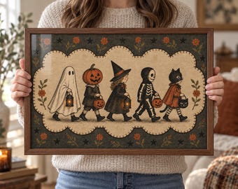 May include: A rectangular framed wall art print featuring a line of five children in Halloween costumes, including a ghost, a pumpkin-headed figure, a witch, a skeleton, and a black cat, set against a beige scalloped background with floral borders.