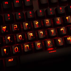 May include: A black computer keyboard featuring custom keycaps with glowing red symbols. The keys display standard alphanumeric characters alongside unique, sharp, angular glyphs illuminated by a red backlight, creating a high-contrast visual effect.