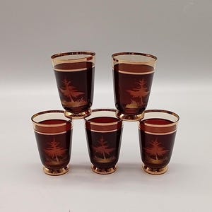 Puede incluir: Juego de seis vasos de chupito de vidrio ámbar con ribete dorado y diseño de árbol.