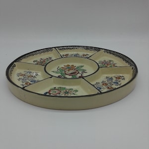 Peut inclure: Un plat de service en céramique blanche avec six sections. Le plat est décoré d'une bordure noire et de motifs floraux dans des tons de bleu, rouge, jaune et vert.