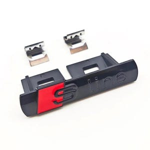 以下が含まれることがあります： 光沢のある仕上げの黒と赤のS-lineエンブレムバッジ。赤いSの文字と黒いlineの文字が特徴です。エンブレムには、プラスチック製の本体の上部に配置された2つの独立した金属製取り付けクリップが含まれています。