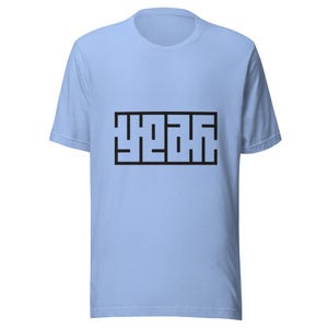 Puede incluir: Camiseta azul claro con un diseño rectangular negro que contiene la palabra "YEAH" en una fuente estilizada y en bloques. La camiseta tiene mangas cortas y cuello redondo.