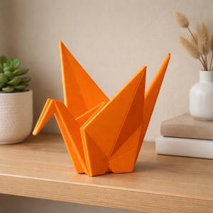 May include: An orange origami crane sculpture sits on a wooden shelf. The paper crane is folded into a detailed geometric shape. A small potted succulent and a vase with dried flowers are in the background. The sculpture is a decorative item.
