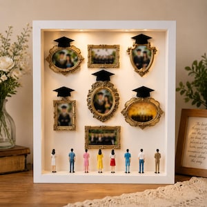 May include: A white shadow box with several ornate gold picture frames, each holding a graduation photo and topped with a black mortarboard. Miniature figures stand below. A framed quote is visible on the right.