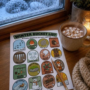 May include: A white paper sheet titled Winter Bucket List with 16 colorful circular and rectangular illustrations of seasonal activities. Each icon has a small checkbox. A wooden pencil rests on the paper next to a mug of hot cocoa with marshmallows.
