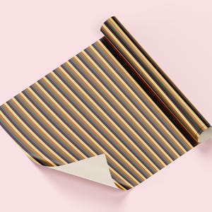 Op de afbeelding: Een rol cadeaupapier met een herhaald patroon van verticale strepen in bruin-, beige- en paars tinten. Het papier is gedeeltelijk uitgerold en onthult een crèmekleurige onderkant. De achtergrond is effen lichtroze.