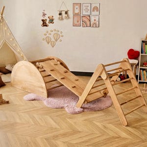 Può includere: Un set di gioco in legno per bambini composto da arco rampicante, rampa e scala. L'attrezzatura da gioco in legno naturale è posizionata su un tappeto rosa. Una tenda teepee e una libreria con giocattoli sono sullo sfondo.