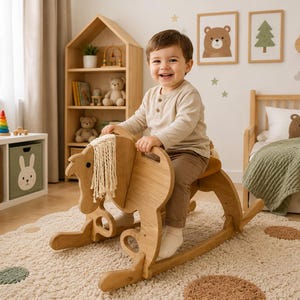 May include: A light brown wooden rocking horse featuring a cream-coloured macrame mane, curved rockers, and cut-out handles. The toy is constructed from smooth, natural-toned wood panels and is designed for a child to sit on and rock back and forth.