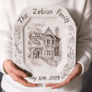 Puede incluir: Una bandeja de cerámica octogonal blanca con una ilustración en tinta negra de una casa de dos pisos. El texto dice The Zebian Family en la parte superior y May 12th, 2026 en la inferior. Enredaderas de fresas decoran los bordes laterales.