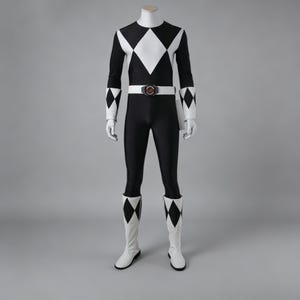 May include: Black and white Power Ranger costume. The full-body suit features a black base with white diamond shapes on the chest and sleeves. The costume includes a white belt with a circular buckle, white gloves, and white boots with diamond accents.