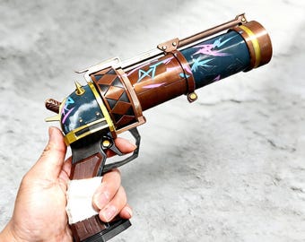 May include: A prop gun with a steampunk aesthetic. The barrel is dark blue with pink and blue floral designs. The body is brown with gold accents and a black handle. The handle is wrapped in white tape.