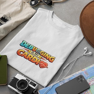 May include: White t-shirt with the text "Debugging is my Cardio" in a colorful, stylized font. The shirt is surrounded by a brown hat, a camera, a notebook, sunglasses, a phone, and a map.