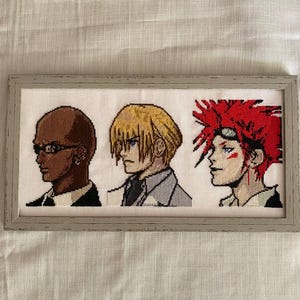 May include: Cross-stitch artwork featuring three anime-style character portraits in profile. The characters have varying skin tones and hair colors, framed in a rectangular, light gray frame. The background is white.