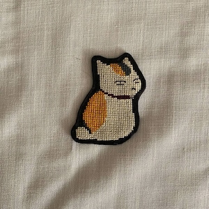 May include: A white ceramic mug with a black handle and the text "But First, Coffee" in a black, handwritten-style font. The mug is on a white surface.