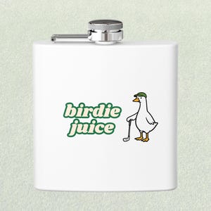 May include: White flask with a silver cap and hinge. The flask features a green and white graphic of a duck wearing a golf hat and holding a golf club, with the words "birdie juice" in green.