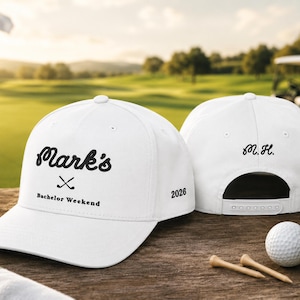 Peut inclure: Deux casquettes de baseball blanches avec du texte et des graphismes noirs. La casquette avant porte le texte Mark's, une icône de clubs de golf croisés et Bachelor Weekend. La casquette arrière affiche les initiales M.H. et l'année 2026 sur le côté.