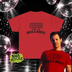 May include: A red short-sleeved t-shirt featuring the black text DANCING IS EVERYTHING EVERYTHING ELSE IS BULLSHIT printed on the front. The shirt is displayed alongside a person wearing the same red t-shirt with the identical black text.