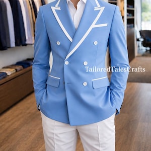 Könnte beinhalten: Hellblauer, zweireihiger Blazer mit weißen Verzierungen und Knöpfen, kombiniert mit einer weißen Hose. Der Blazer hat weiße Paspelierungen an Revers und Taschen. Der Text "TailoredTalesCrafts" ist auf der rechten Seite des Bildes zu sehen.