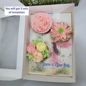 May include: A white box containing a greeting card decorated with buttercream flowers in shades of pink, yellow, and green. The card features an illustration of a girl and the text "Have a Nice Day". The box also has the text "You will get 3 sets of templates".