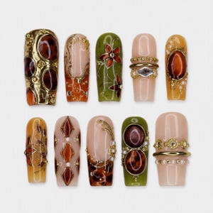 Könnte beinhalten: Ein Set aus zehn künstlichen Fingernägeln mit verschiedenen Designs in Olivgrün, Bernstein und Nude. Die Nägel sind mit goldenen Metallic-Akzenten, braunen Cabochons in Schildpatt-Optik, Blumenmustern und kleinen weißen Perlen verziert.