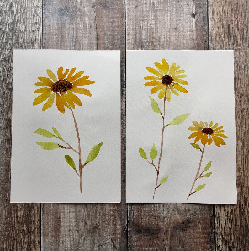 Puede incluir: Dos acuarelas de girasoles amarillos con tallos y hojas verdes sobre papel blanco.