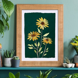 Puede incluir: Una impresi&oacute;n enmarcada de una ilustraci&oacute;n bot&aacute;nica con tres girasoles amarillos con hojas verdes sobre un fondo verde oscuro.