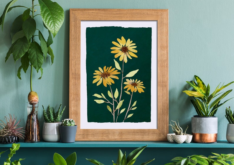 Puede incluir: Una impresi&oacute;n enmarcada de una ilustraci&oacute;n bot&aacute;nica con tres girasoles amarillos con hojas verdes sobre un fondo verde oscuro.