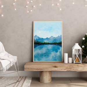 May include: A framed watercolor painting of a mountain lake scene with a blue sky and white clouds. The lake is reflecting the mountains and sky. The painting is on a wooden shelf with a white lantern and candles.