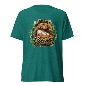 May include: A heathered teal short-sleeve t-shirt featuring a graphic of an anthropomorphic bear character with long wavy hair, wearing a cap and gold chains, with arms crossed. The text Bougie Behavior is printed in a stylised gold and black font.