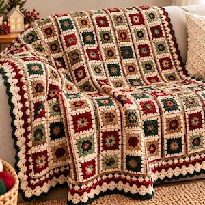 May include: A handmade crochet blanket featuring a repeating granny square pattern in shades of deep red, forest green, tan, and cream. The throw has a scalloped border in cream and dark green, with a textured finish throughout the design.
