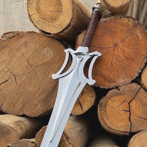 K&ouml;nnte beinhalten: Ein Schwert aus silberfarbenem Metall mit einer zweischneidigen Klinge, einer spitzen Spitze und einem stilisierten, geschwungenen Parierst&uuml;ck. Der Griff ist mit braunem Material umwickelt und der Knauf ist eine einfache silberne Metallkappe.