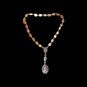 May include: A rosary featuring translucent, amber-colored, oval-shaped beads strung on a gold-toned chain. The rosary includes a silver-toned centerpiece depicting a religious figure and a dangling oval pendant with a silver-toned embossed image.