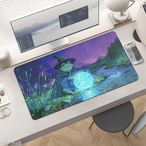 May include: A rectangular mousepad featuring a whimsical illustration of a frog wizard. The frog is depicted wearing a wizard hat and cloak, holding a glowing blue orb. The background shows a stream and a purple and blue night sky.