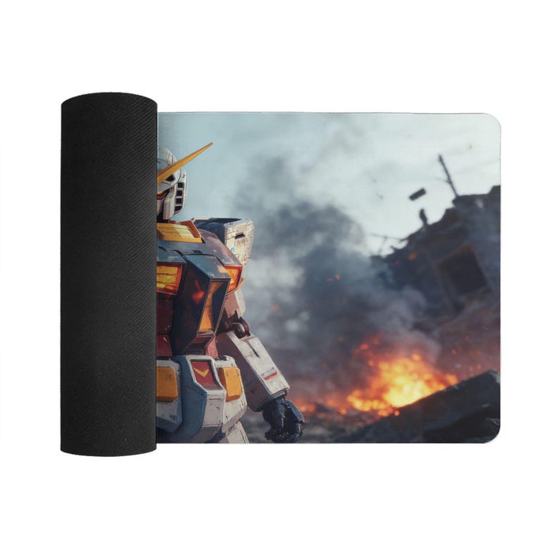 May include: A rolled-up black yoga mat with a printed design. The design features a detailed image of a Gundam robot standing in a war-torn environment with flames and smoke. The robot is primarily white, blue, and yellow.