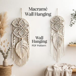 May include: Two off-white macramé wall hangings featuring circular frames with intricate knotted geometric patterns and a central leaf-shaped fringe element. The text Macramé Wall Hanging Wall Hanging PDF Pattern is displayed in the center.