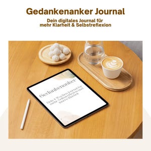 Op de afbeelding: Een tablet met de tekst Gedankenanker, Dein 4-Wochen-Journal für mehr Selbstreflexion und innere Klarheit, een witte stylus, een houten dienblad met een glas water en een koffiekopje, en een klein houten bordje met witte lekkernijen.