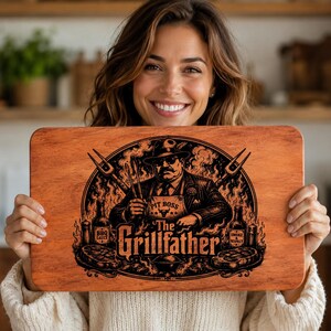 Peut inclure: Planche à découper rectangulaire en bois avec une finition marron foncé. La planche présente un graphisme noir d'un homme en costume et chapeau, tenant des ustensiles de grillade, avec le texte "The Grillfather". Comprend des images de steaks et de bouteilles.