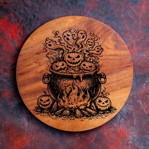 May include: A circular wooden chopping board with a Halloween design. The design shows a cauldron with jack-o'-lanterns, flames, and ghosts. The board is made of light brown wood and has a dark brown edge.