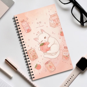 Könnte beinhalten: Ein spiralgebundenes Notizbuch mit pfirsichfarbenem Einband, das eine weiße Katze zeigt, die einen Pfirsich umarmt. Der Einband enthält Illustrationen von Pfirsichgetränken, Milchkartons sowie den Text "日記" und "notes & dreams".