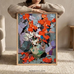 May include: A framed floral still life painting. The artwork features vibrant orange and white flowers in a green vase against a backdrop of blue, purple, and gray brushstrokes. The text "MERRITT LANE" is at the bottom.