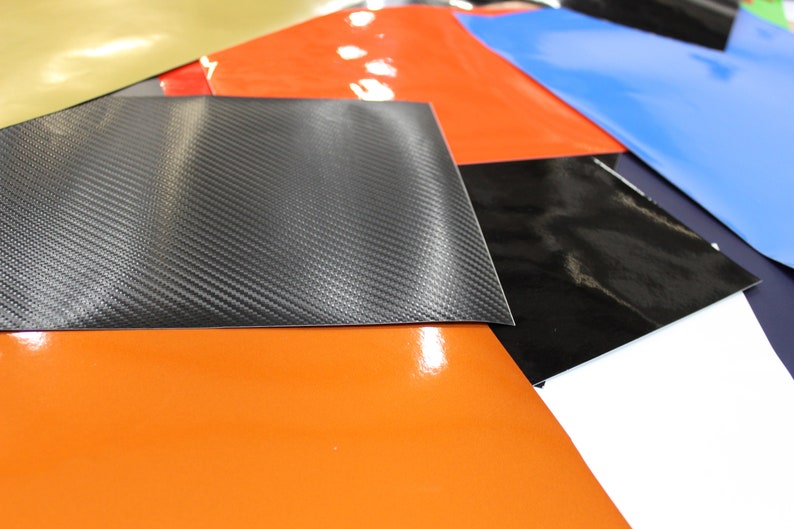 May include: A selection of coloured vinyl sheets, including black, blue, orange, red, gold, and a carbon fibre pattern.