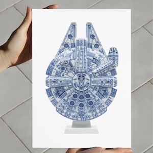 Puede incluir: Una escultura de cerámica azul y blanca del Halcón Milenario. La nave espacial está intrincadamente detallada con un diseño tradicional de porcelana azul y blanca. La escultura está montada sobre una base blanca.