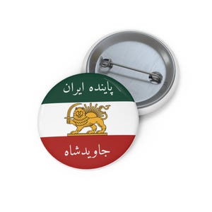 May include: A round button pin featuring the Iranian flag design. The pin has a white background with a green stripe at the top and a red stripe at the bottom. The center features a golden lion holding a sword. The text in Farsi is also visible.