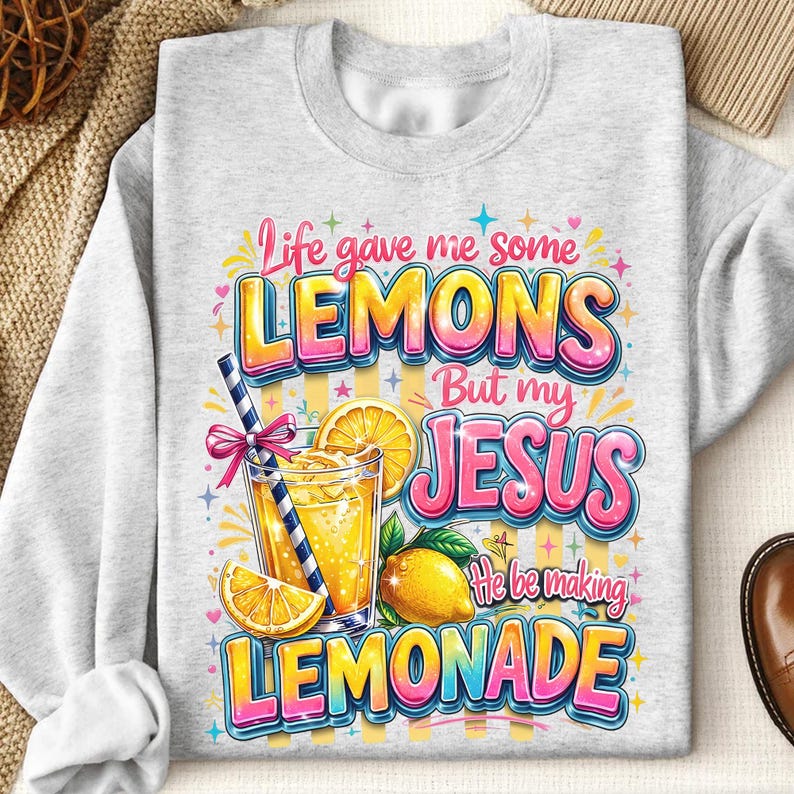 K&ouml;nnte beinhalten: Hellgraues Sweatshirt mit farbenfroher Grafik. Die Grafik zeigt den Text "Life gave me some LEMONS But my JESUS He be making LEMONADE" mit einem Glas Limonade, Zitronenscheiben und einer ganzen Zitrone.