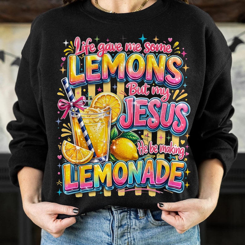 K&ouml;nnte beinhalten: Schwarzes Sweatshirt mit einem farbenfrohen Aufdruck: "Life gave me some lemons but my Jesus he be making lemonade." Das Design zeigt ein Glas Limonade, Zitronenscheiben und eine ganze Zitrone.