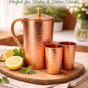 Może przedstawiać: Biały ceramiczny kubek z czarnym uchwytem i napisem "But First, Coffee" pogrubioną czcionką. Kubek stoi na drewnianej powierzchni. Kubek ma 10 cm wysokości.