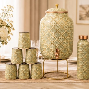 May include: A large cylindrical beverage dispenser with a copper-colored spigot and lid, accompanied by six matching tumblers and a tall water bottle. Each item features a light green and gold quatrefoil pattern on a metallic surface.