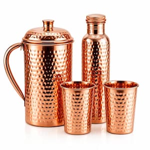 May include: A set of hammered copper drinkware consisting of a large pitcher with a lid and handle, a tall water bottle with a cap, and two matching tumblers. Each piece features a consistent dimpled texture across the polished metallic surface.
